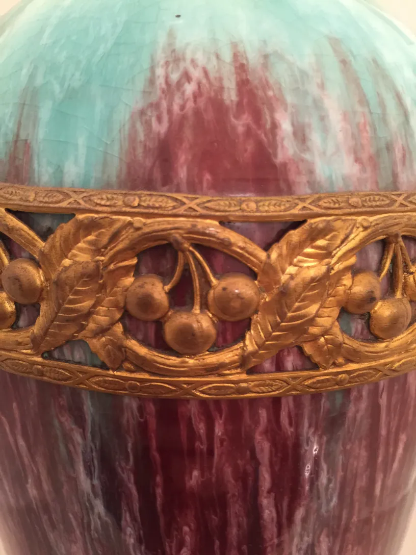 Vase ancien en céramique avec des teintes vertes et rouges, orné de détails dorés de feuilles et fruits.