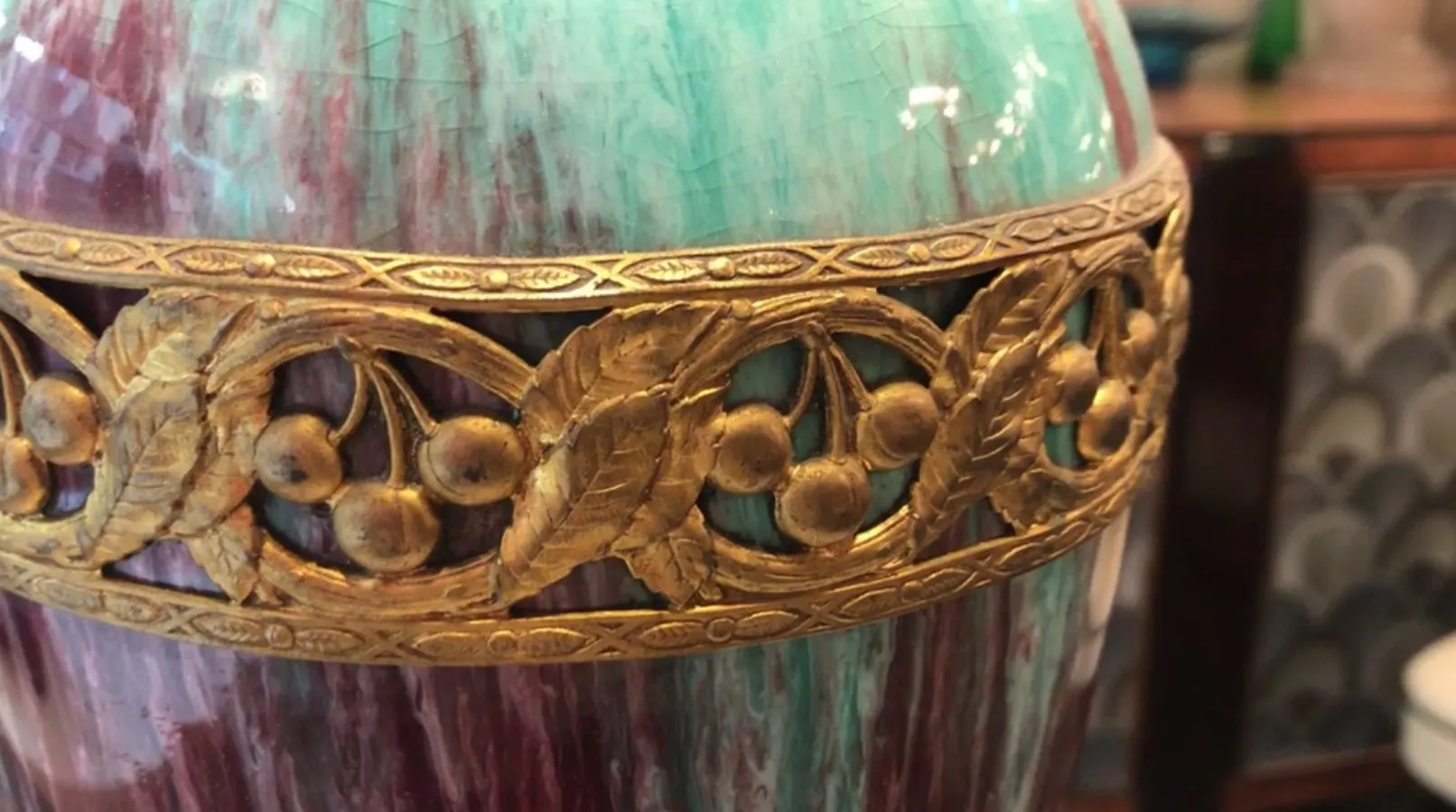 Cerámica antigua decorada con detalles dorados y fondo colorido.