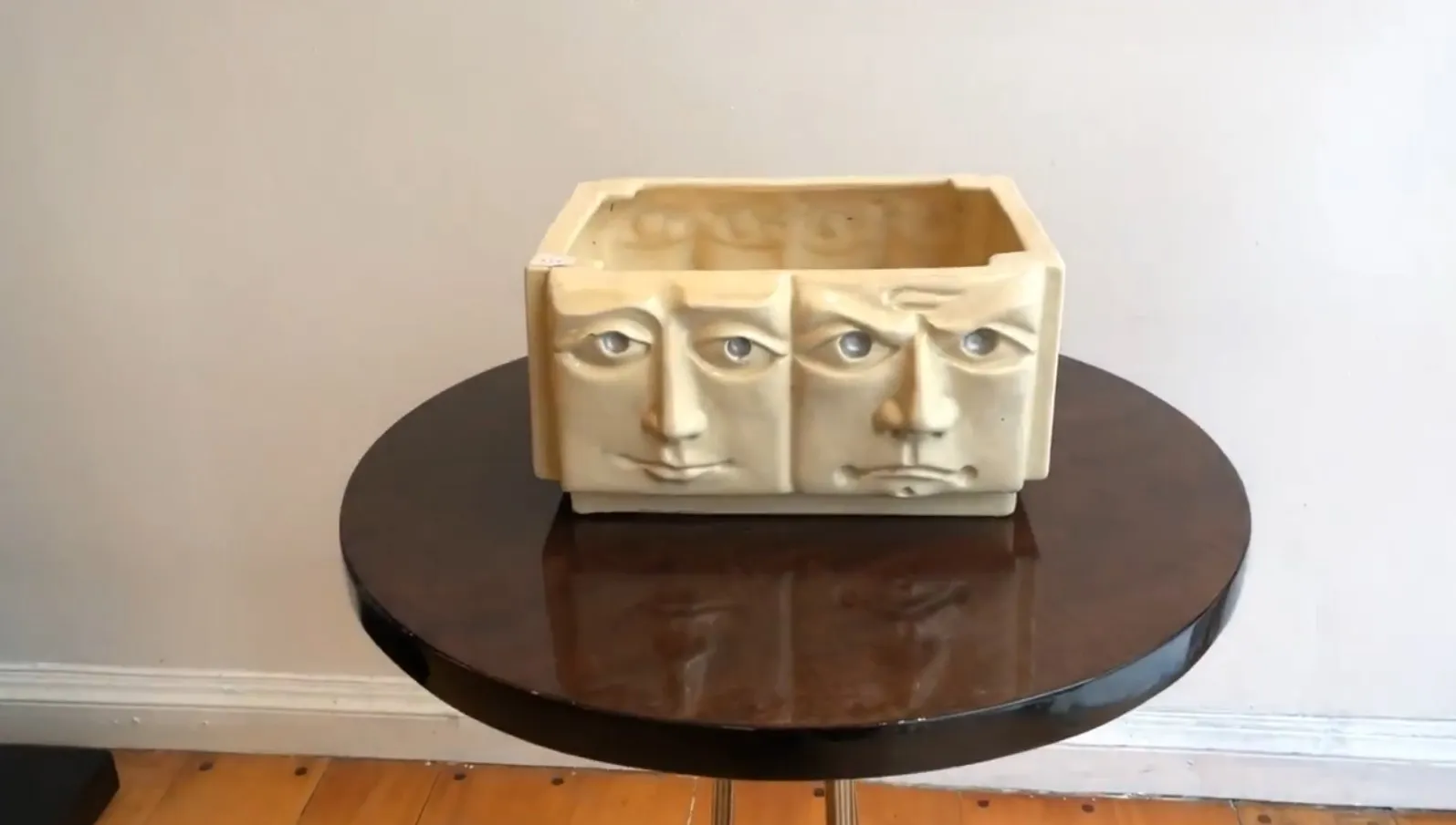 Cerâmica antiga com três rostos em fundo claro