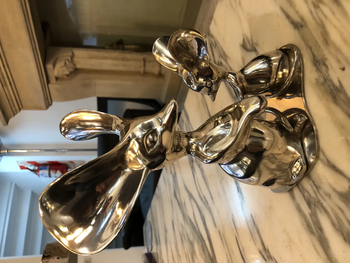 Antique animal sculpture in shiny metal on marble surface.