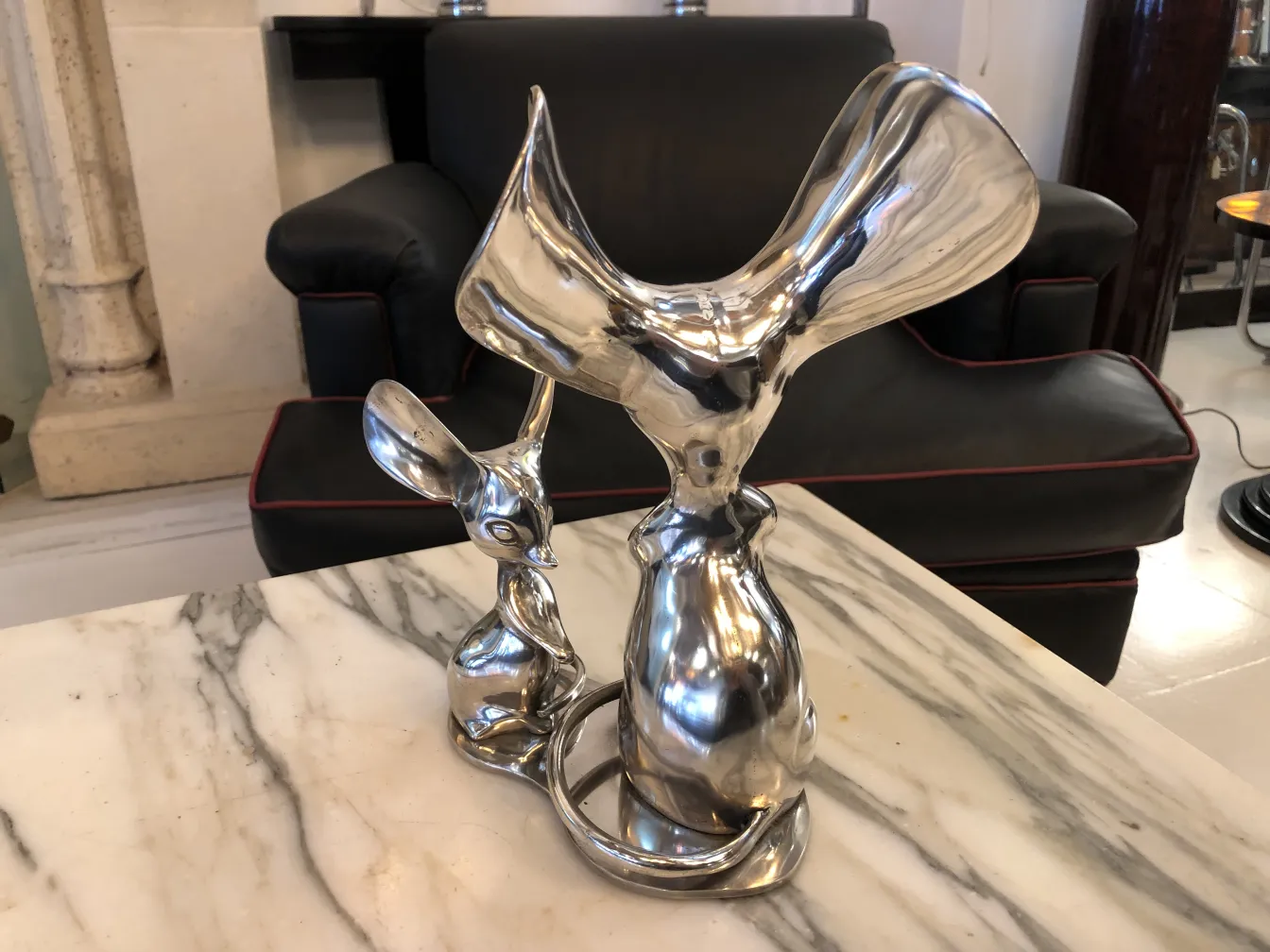 Escultura antigua en metal con forma de rana y conejo sobre mármol