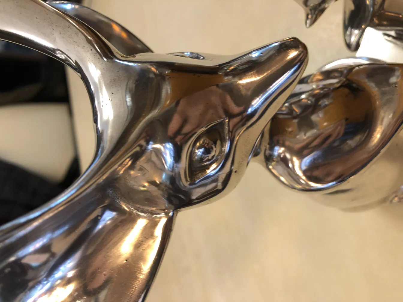 Escultura antiga representando dois animais, brilha ao refletir a luz.