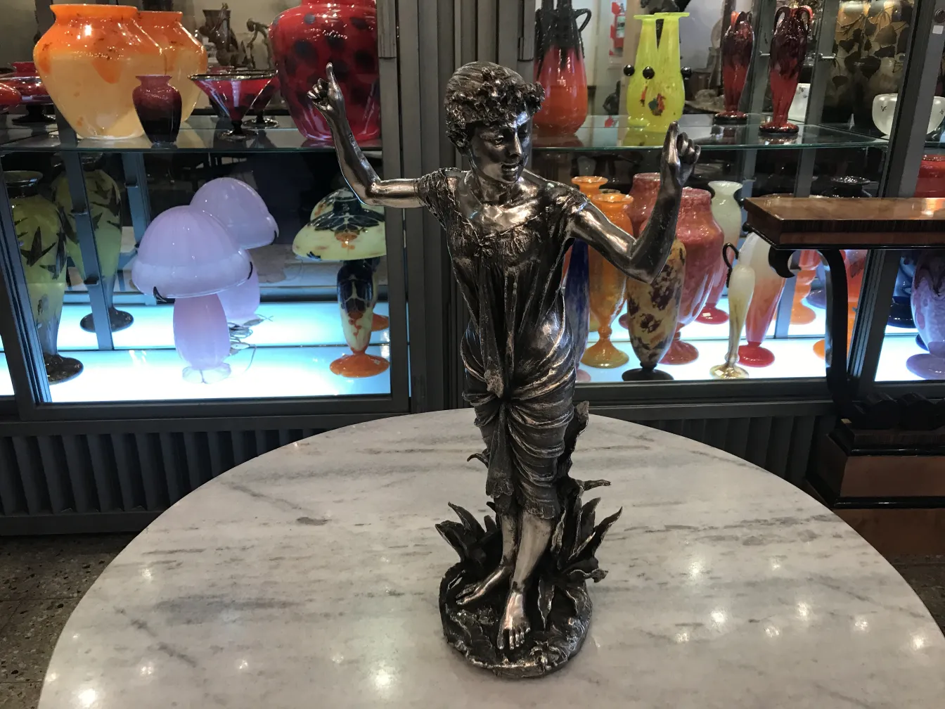 Escultura antiga de figura feminina em um ambiente elegante com vasos coloridos.