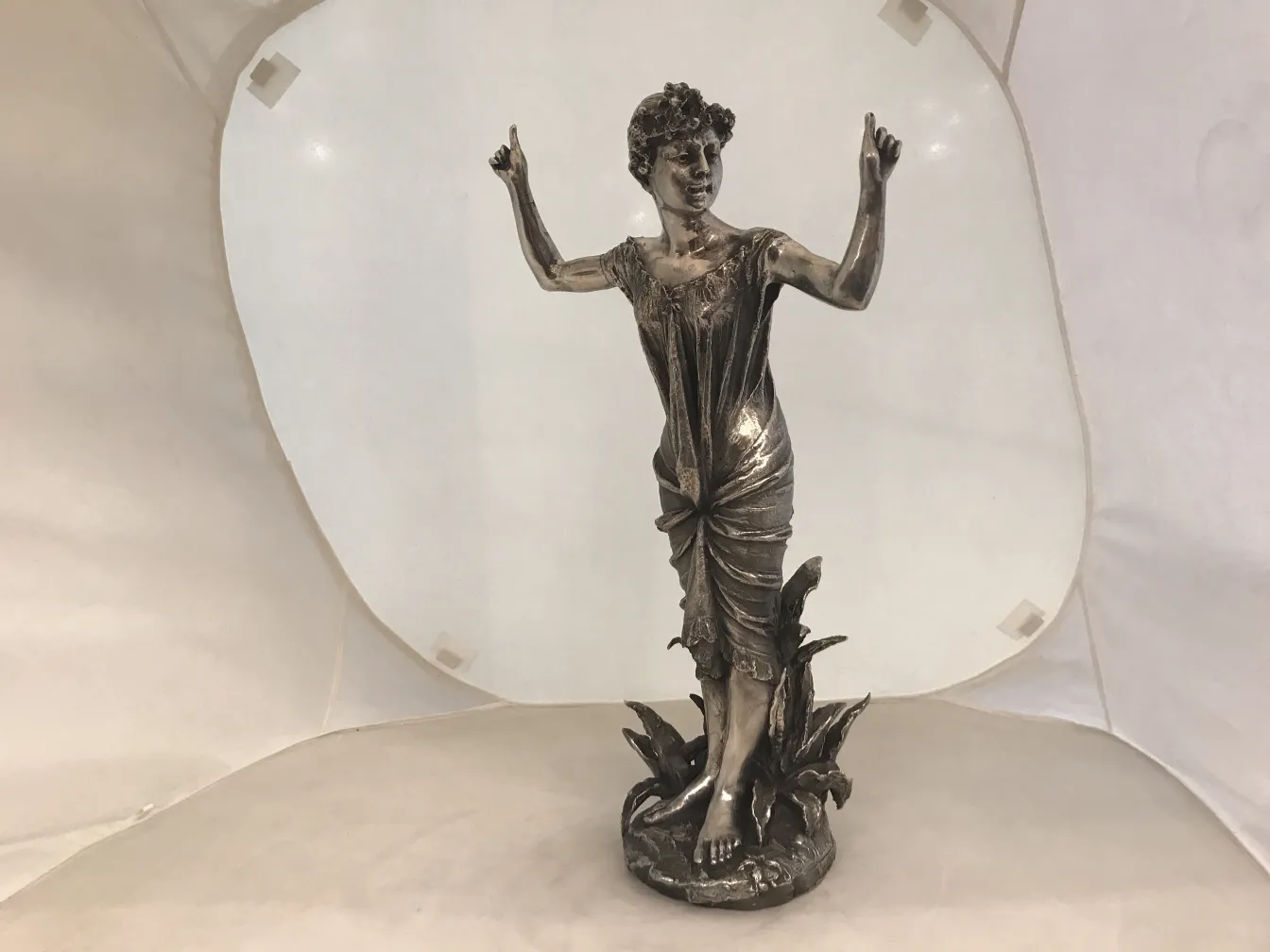 Antike Skulptur einer Frau, die unter Pflanzen gestikuliert.