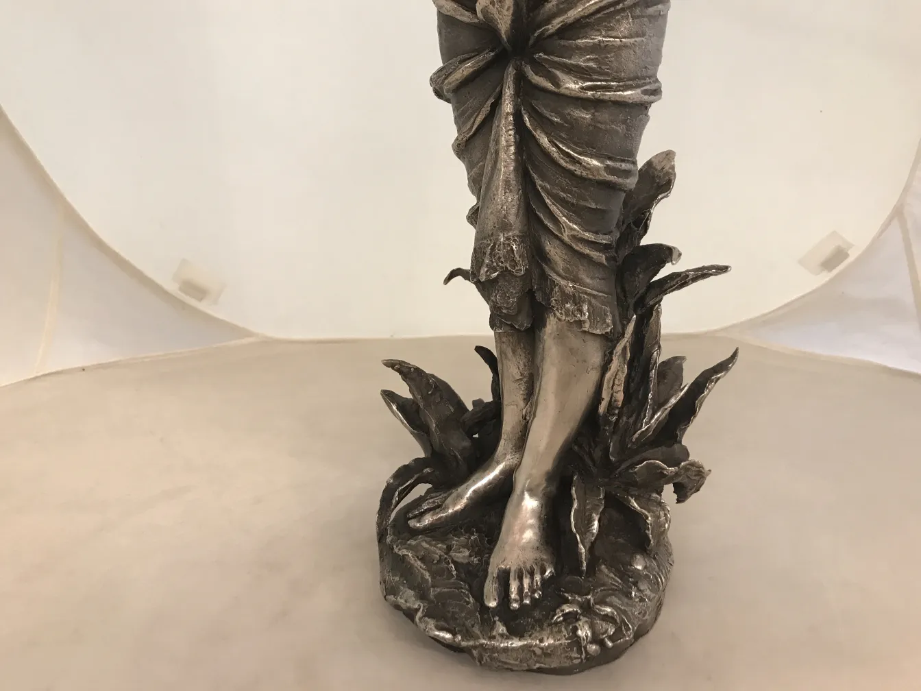 Escultura antigua con figura en movimiento y base decorativa