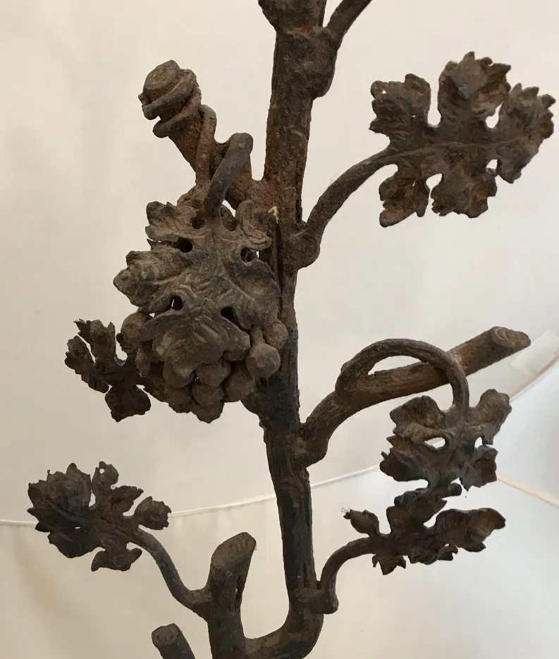 Antike Skulptur, die Äste und Blätter aus Eisen darstellt, mit künstlerischen Details.