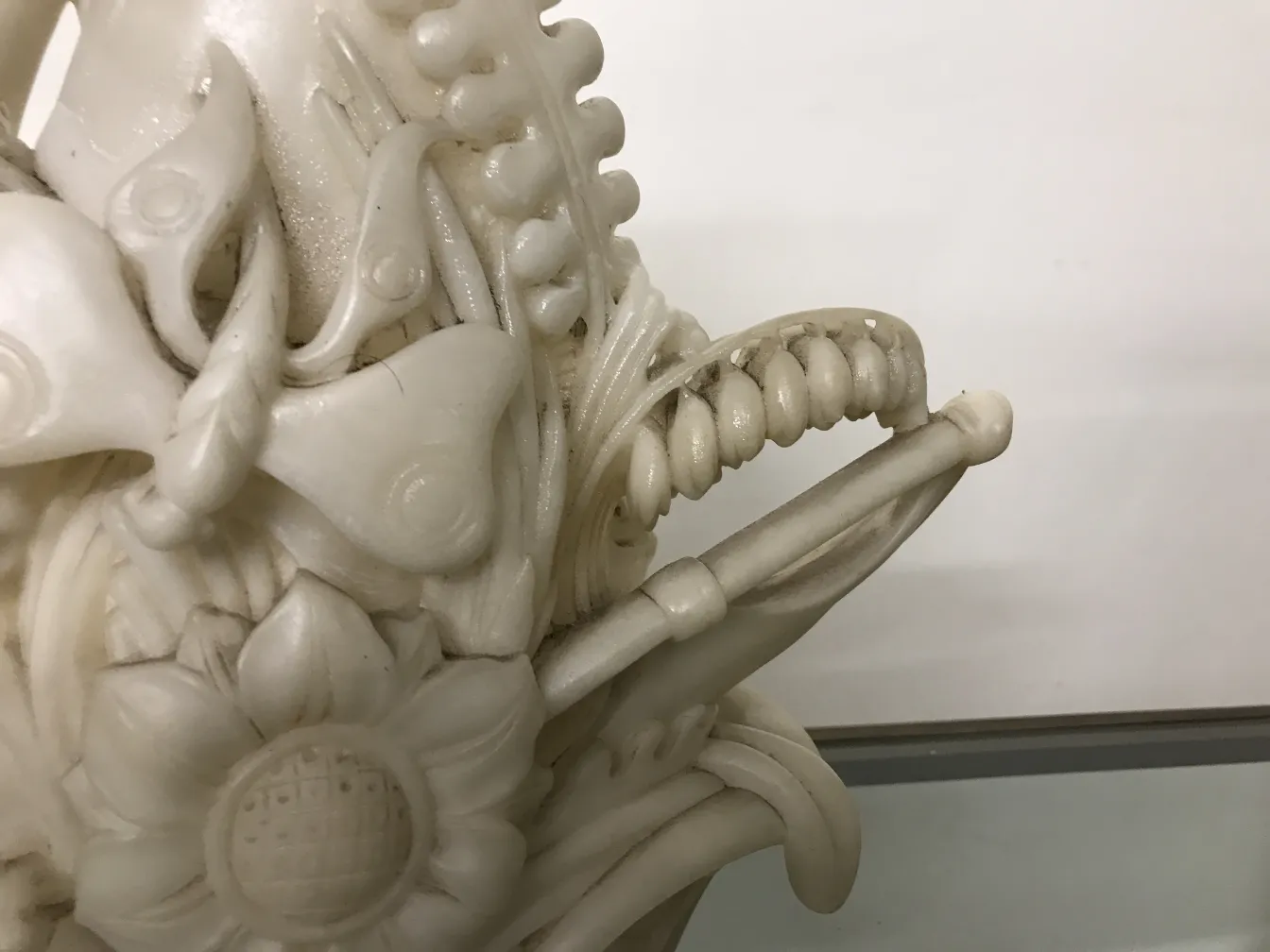 Alte Skulptur mit aufwendigen Blumen- und Schmetterlingsdesigns.