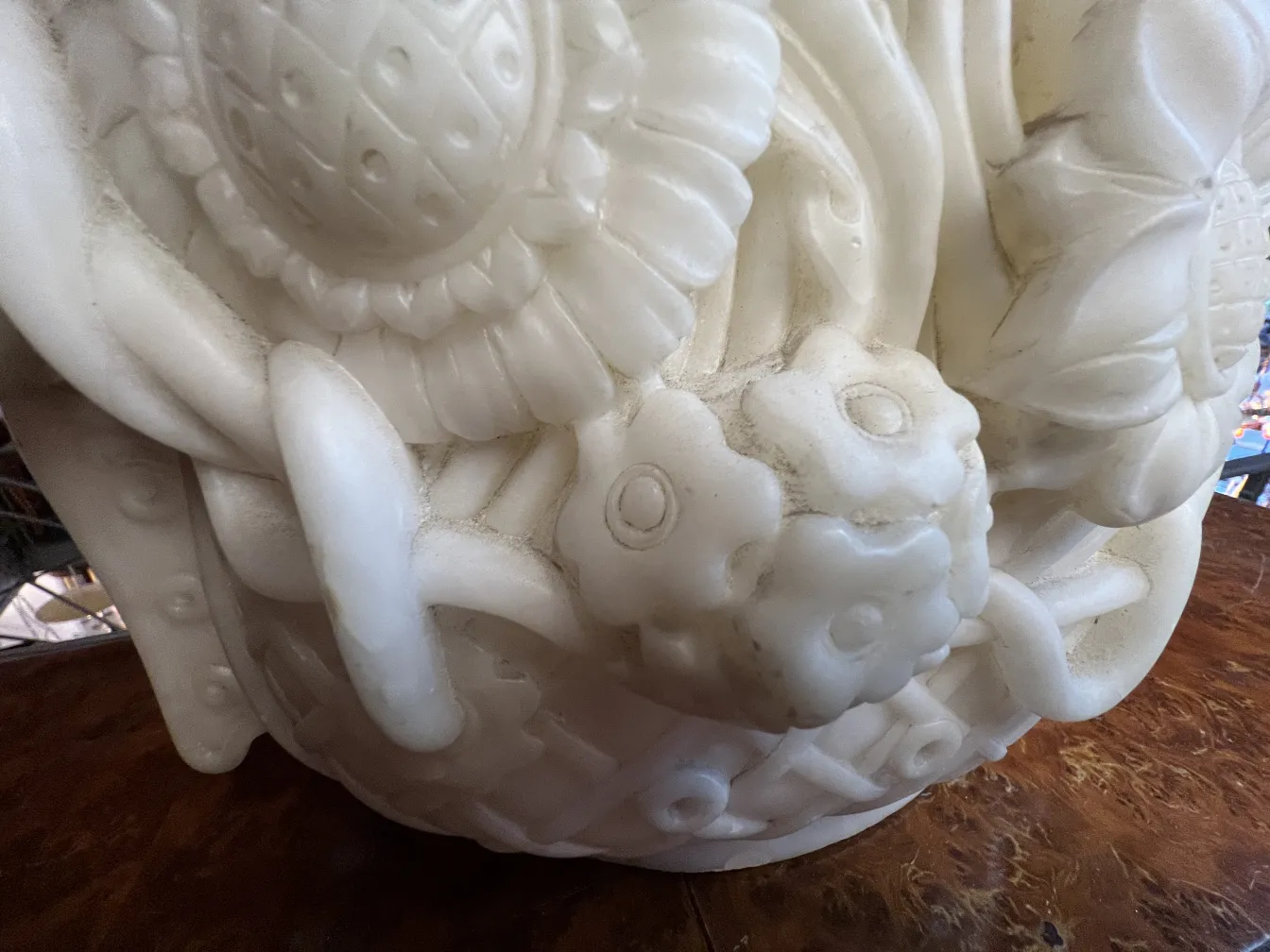 Scultura antica con dettagli floreali in rilievo, sfondo elegante.