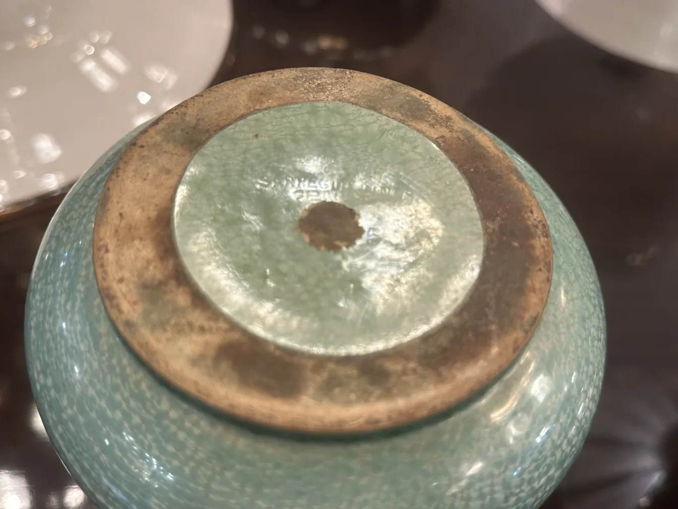 Base de cerâmica antiga com esmalte azul, ambiente acolhedor.