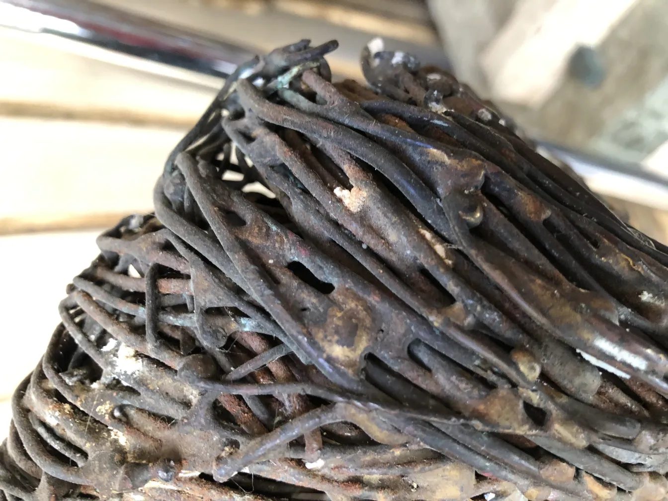 Alte Skulptur mit sichtbaren abstrakten Details, umgeben von Holz.