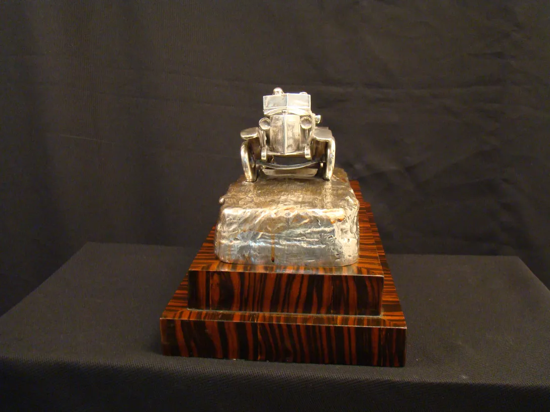 scultura antica di un'auto su una base decorativa