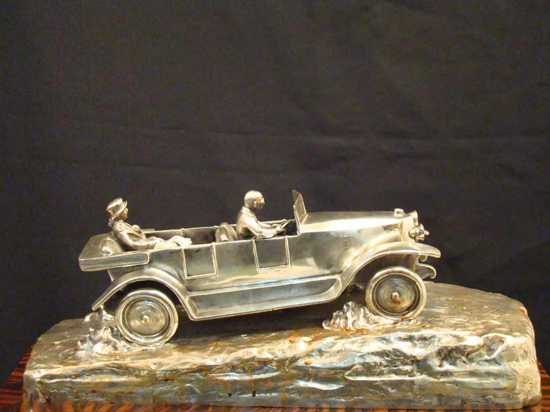 Antique sculpture depicting a car with two figures