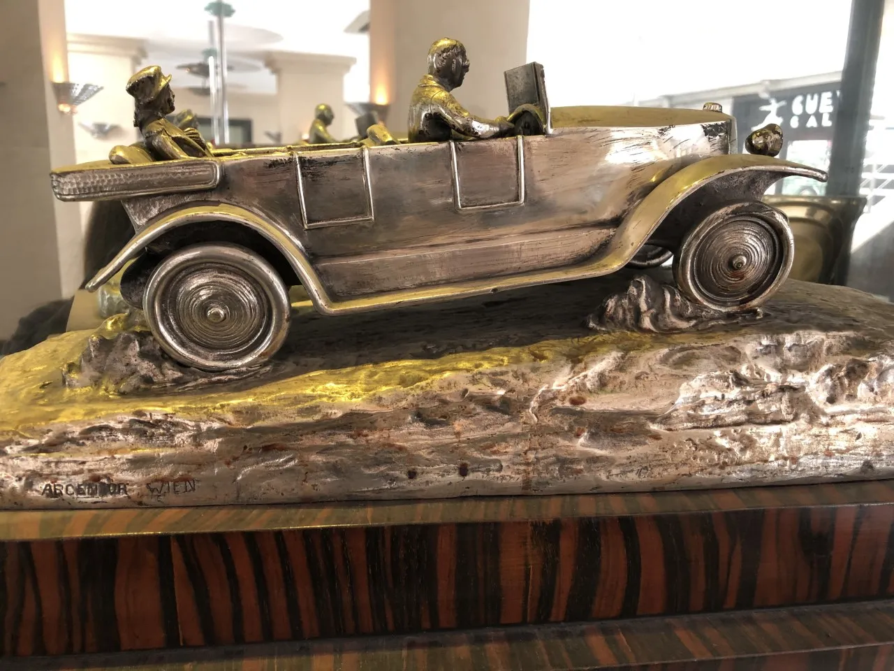 Escultura antigua de un carro con figuras sentadas en él.