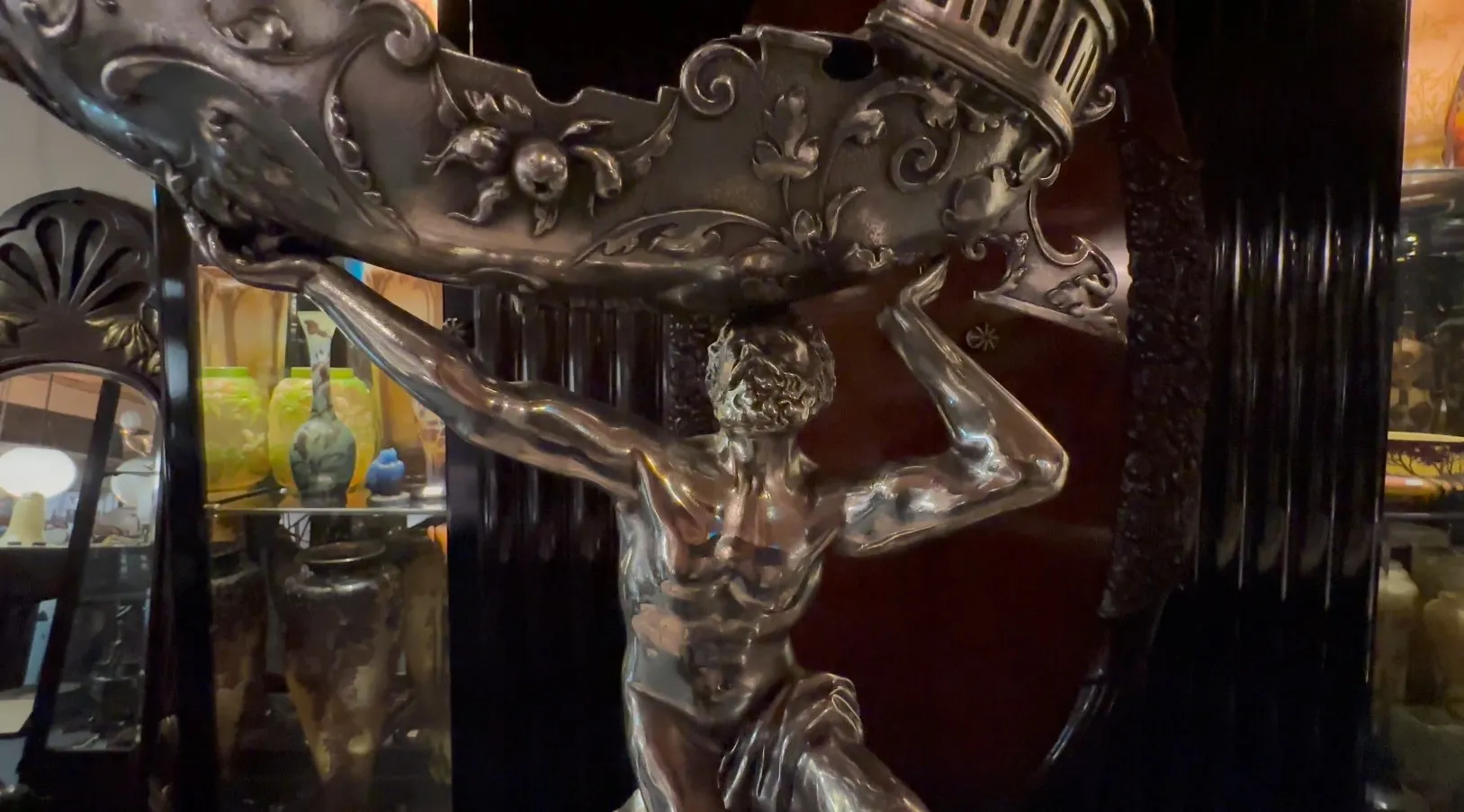 escultura antiga de um homem levantando uma lâmpada decorativa