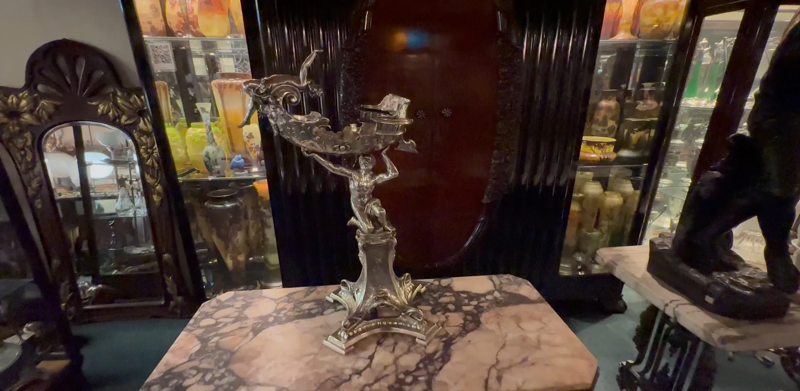 escultura antigua de diseño elegante con detalles decorativos, rodeada de objetos de antigüedades