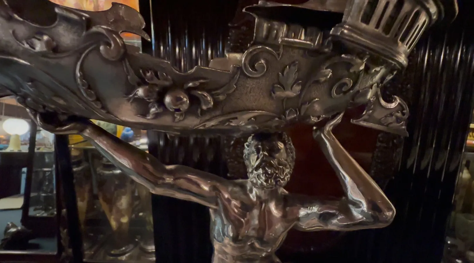 escultura antigua con una figura masculina sosteniendo una base decorada