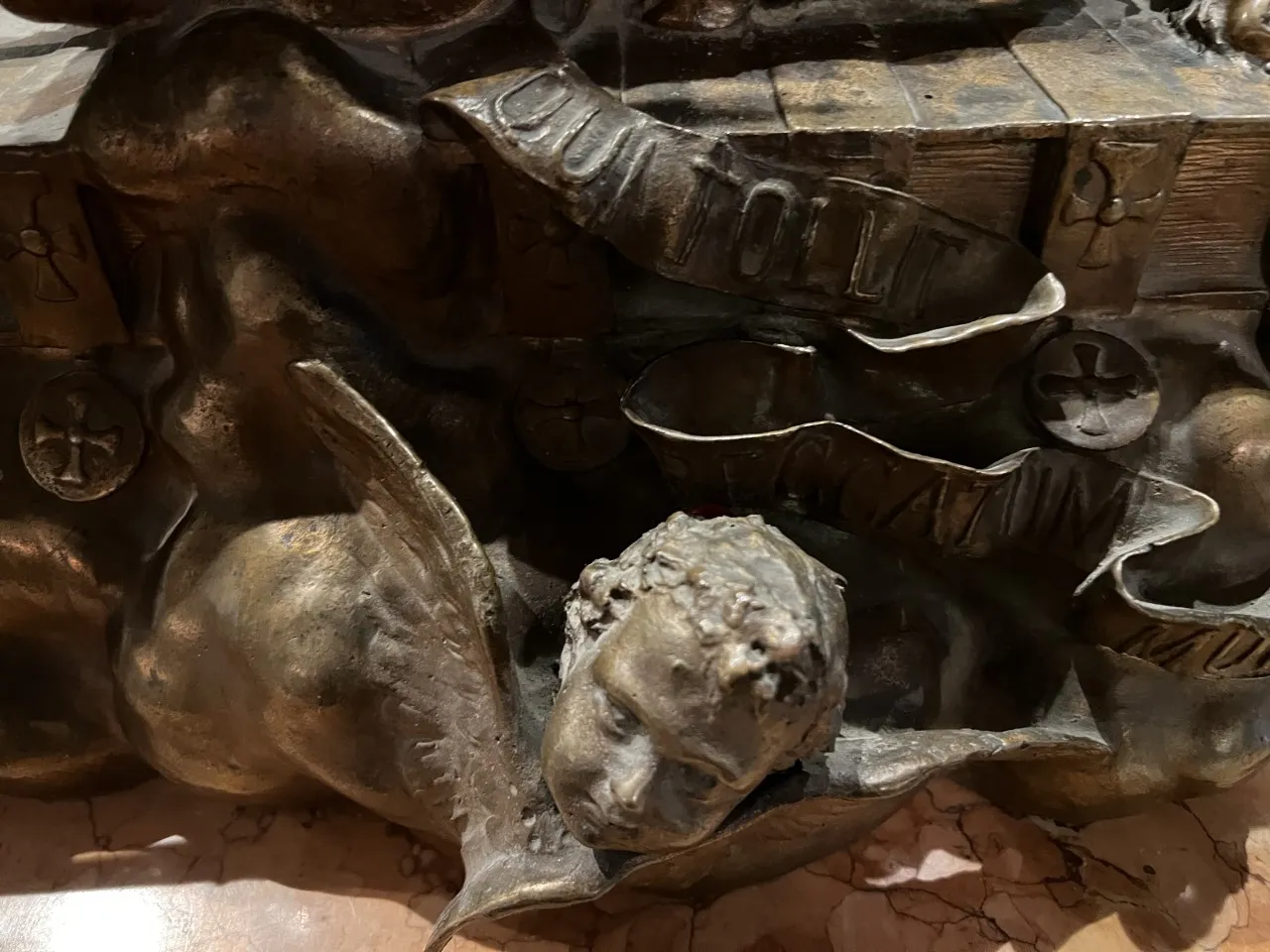 Sculpture ancienne d'un ange avec un visage serein et des ailes déployées.