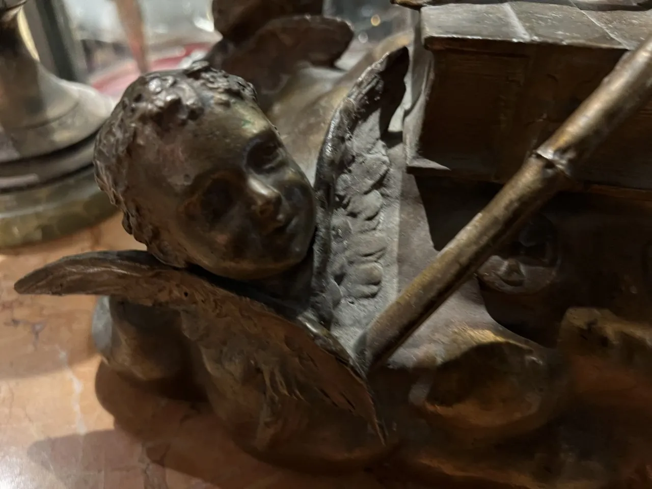 antike Skulptur eines Engels mit ruhigem Ausdruck, umgeben von verzierten Details