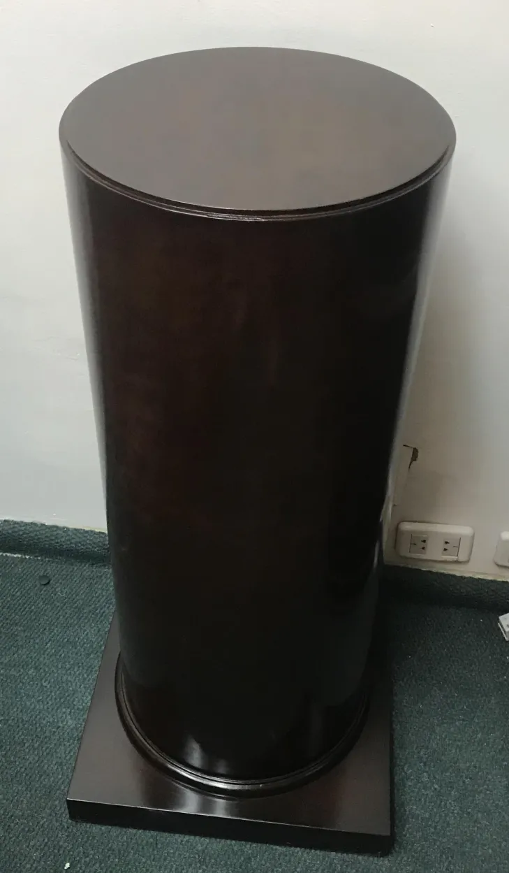 Canto de uma coluna decorativa antiga com base, em ambiente neutro.