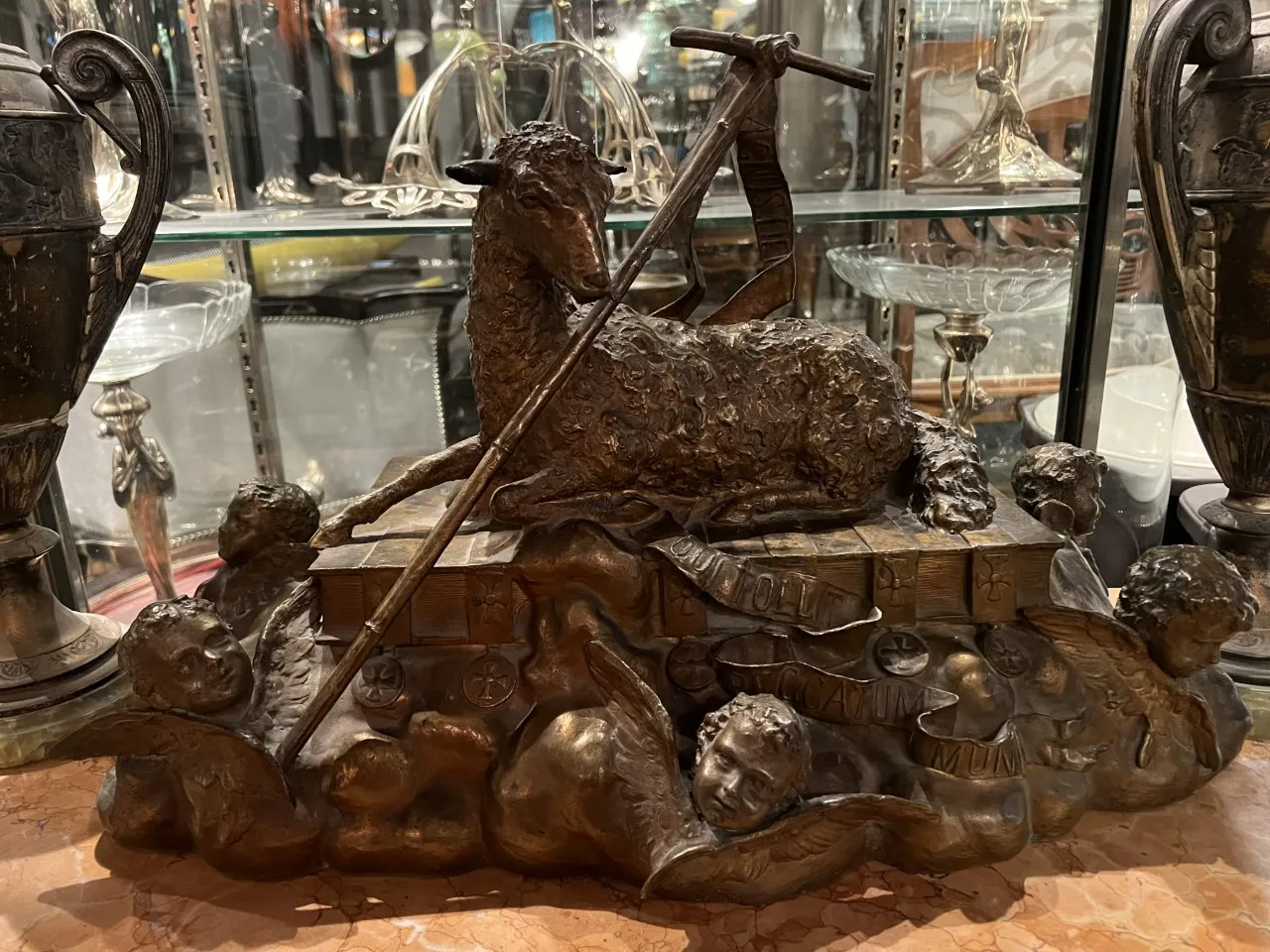 Escultura antiga apresentando um cordeiro e querubins em um ambiente elegante