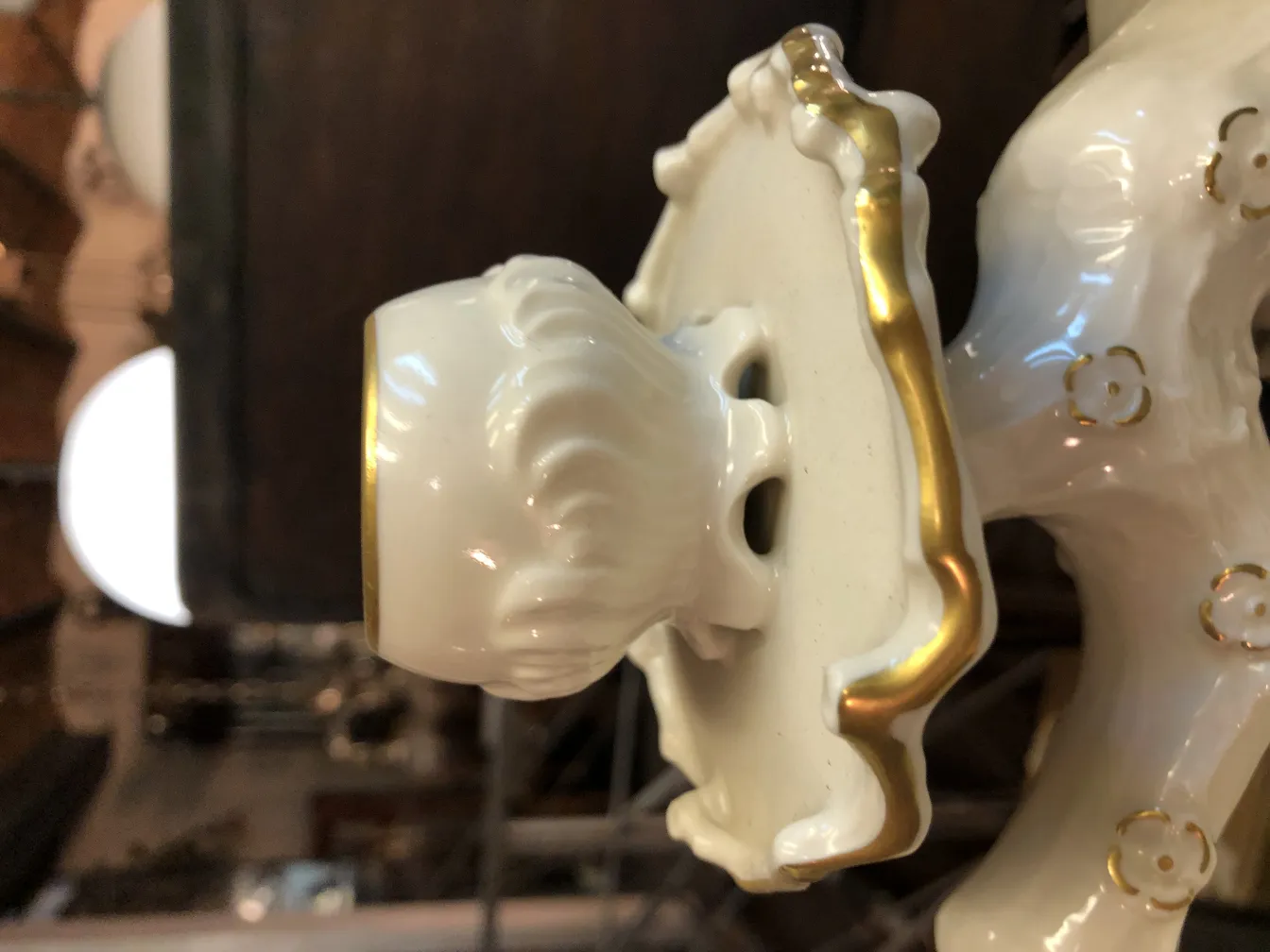 Dettagli di un'antica ceramica bianca con finiture dorate, che mostra la sua ornamentazione e stile decorativo in un ambiente classico.