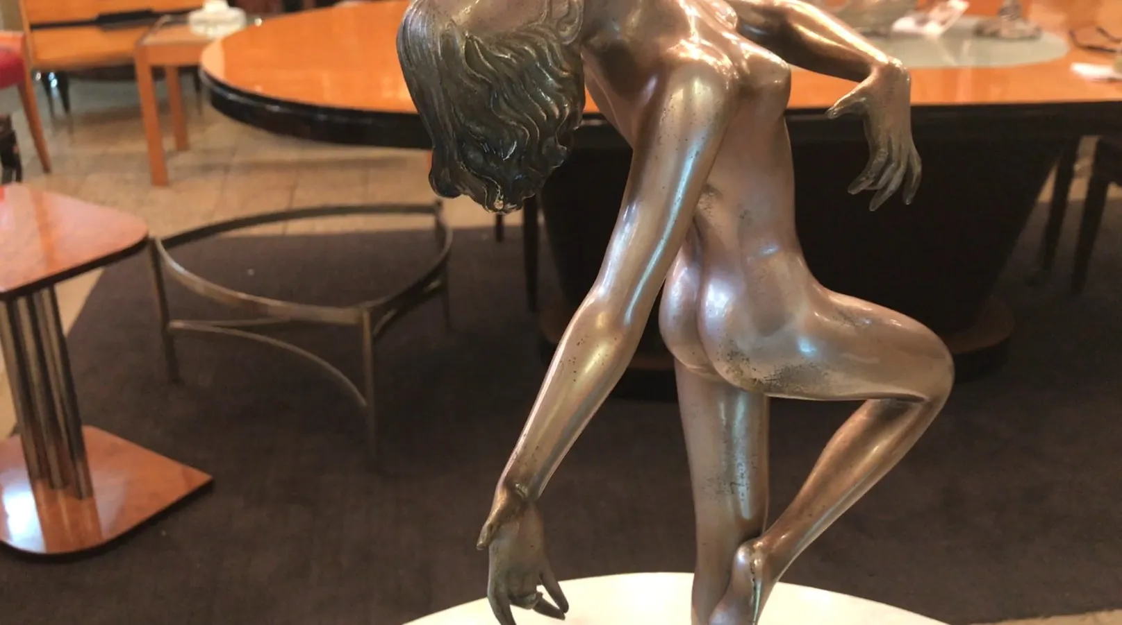 Scultura antica di figura in posa delicata, sfondo con tavolo