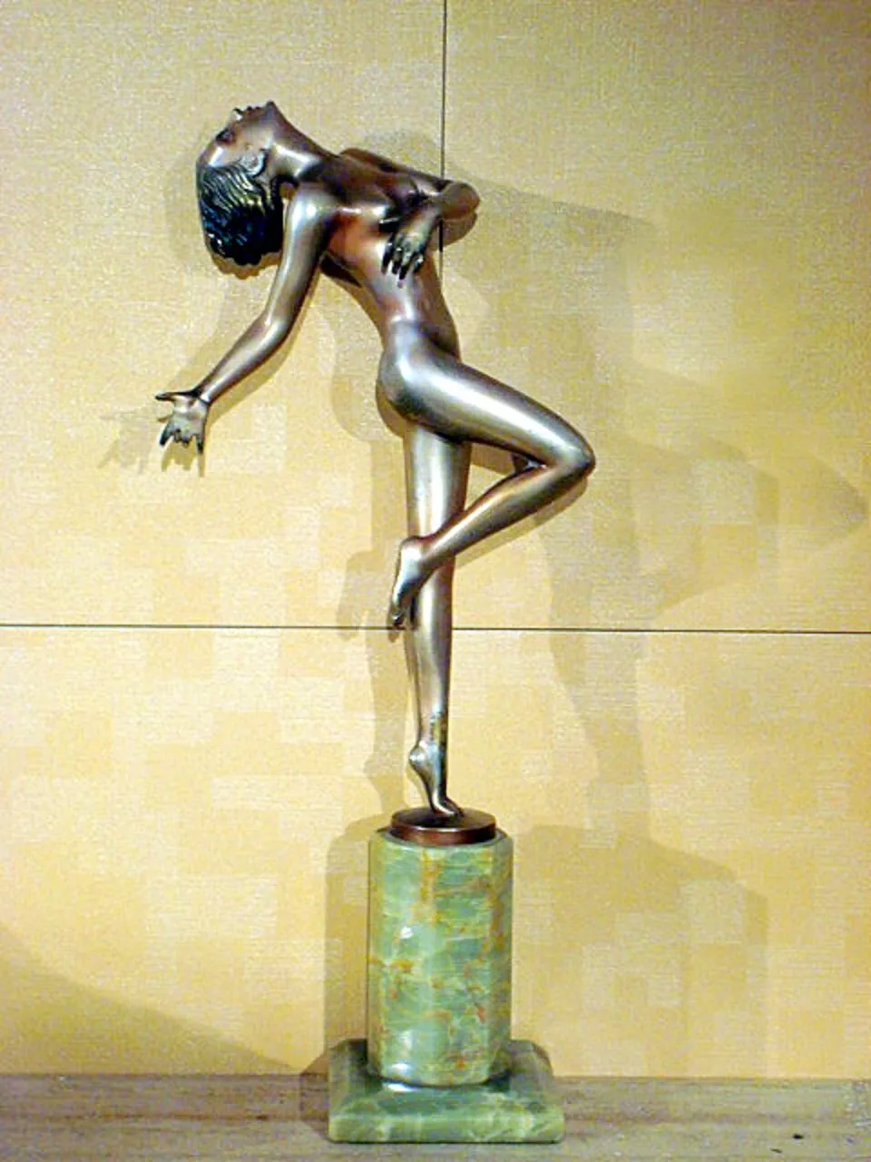 escultura antiga de uma mulher dançante em pedestal verde