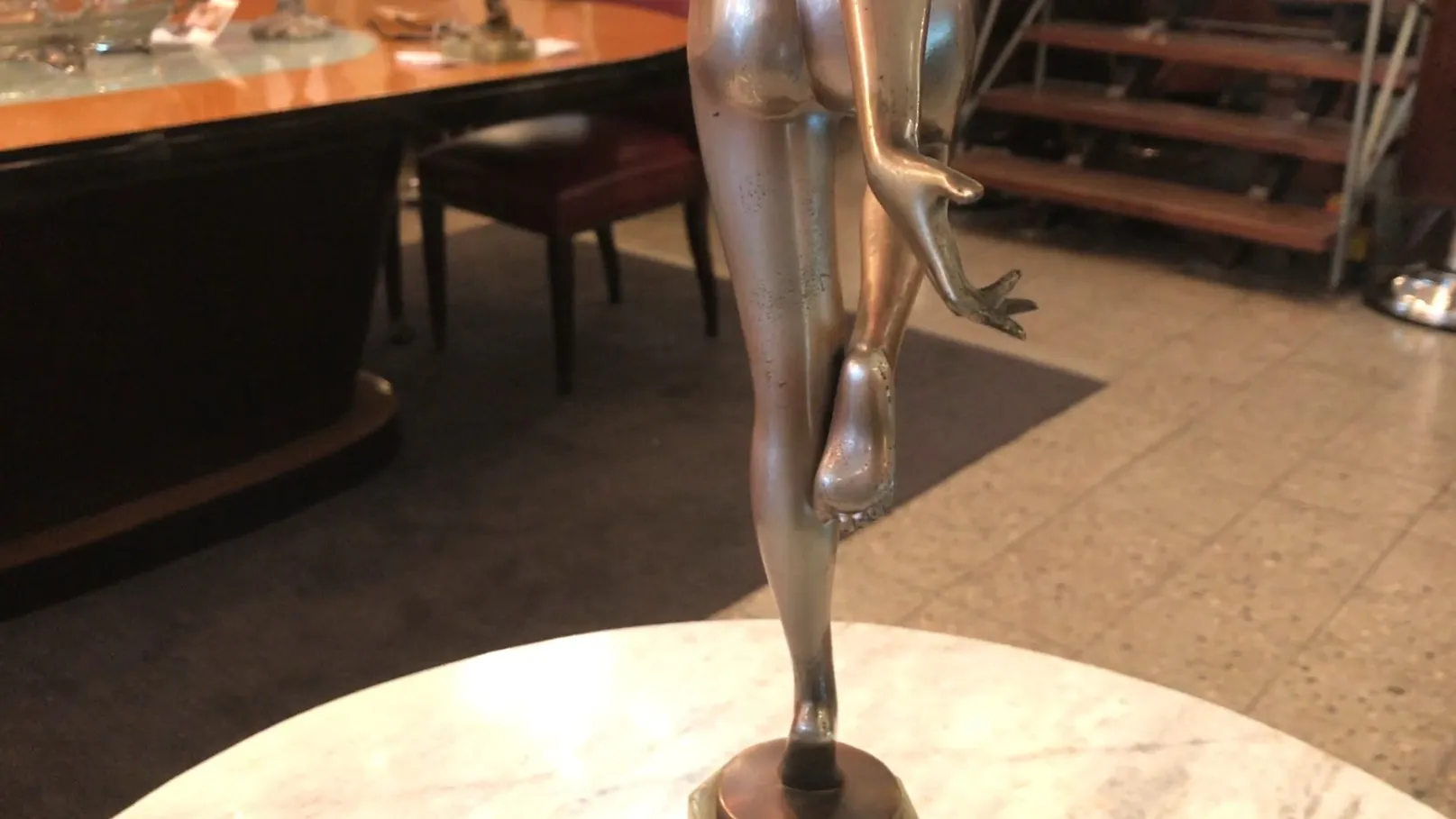 Escultura antigua con figura en pose elegante sobre pedestal