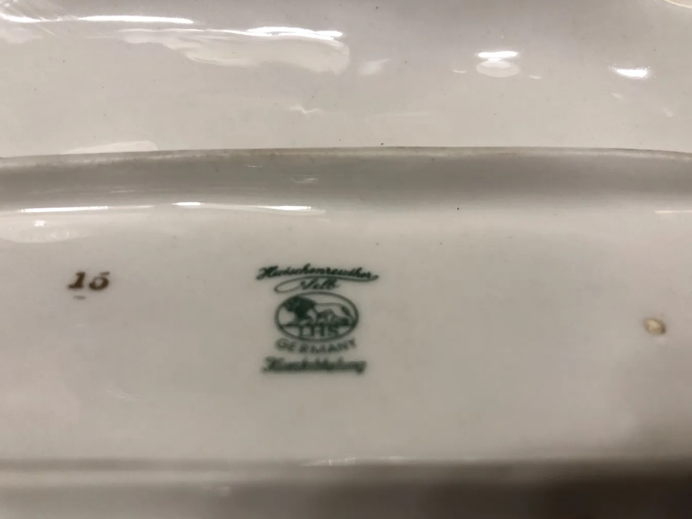 Assiette en céramique ancienne, avec un design vert et une marque allemande.