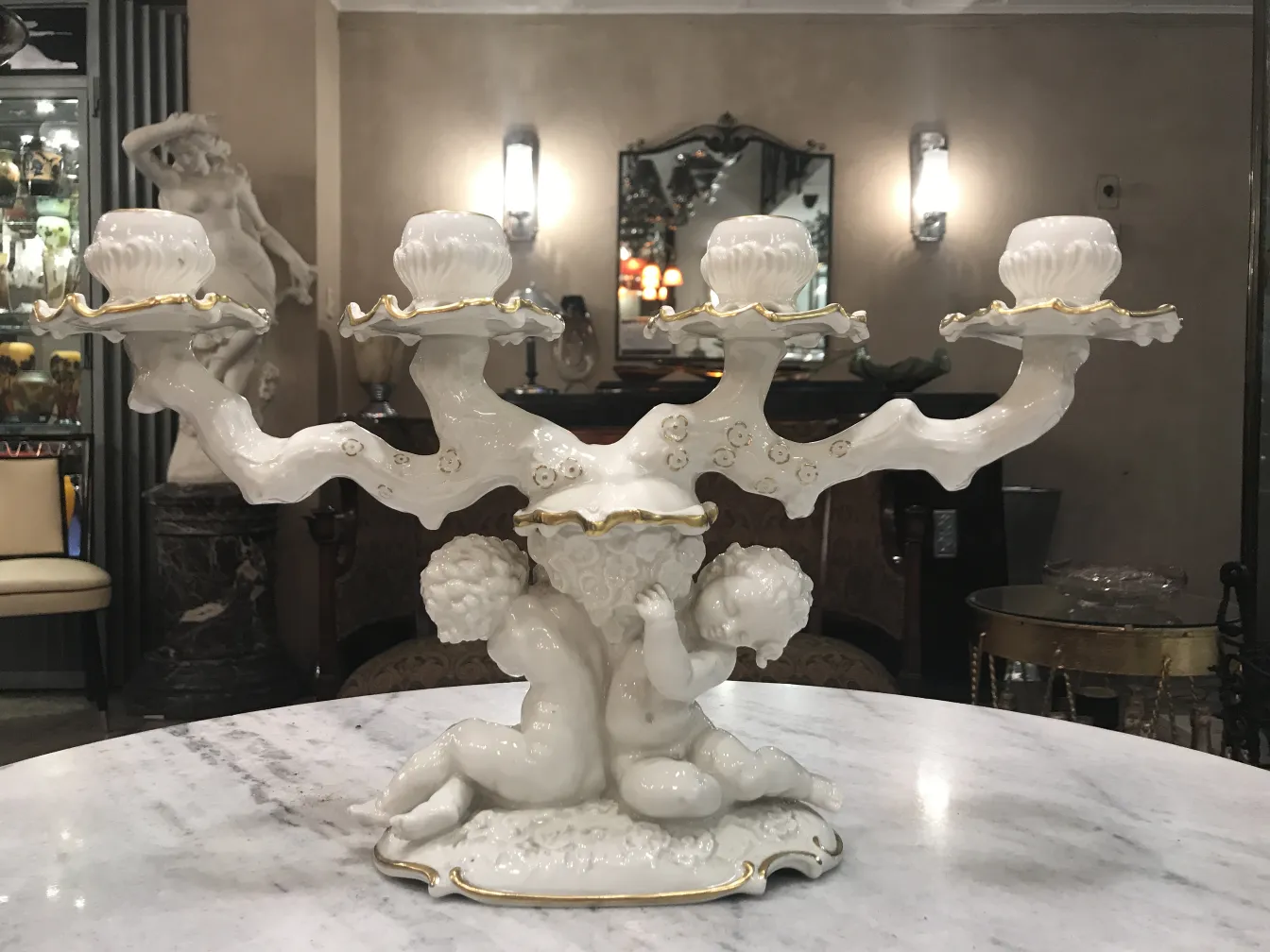 Candelabro antico in ceramica con cherubini in un ambiente elegante.