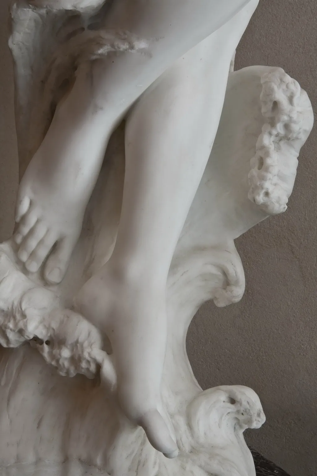 detalle de escultura antigua con pies y base decorativa