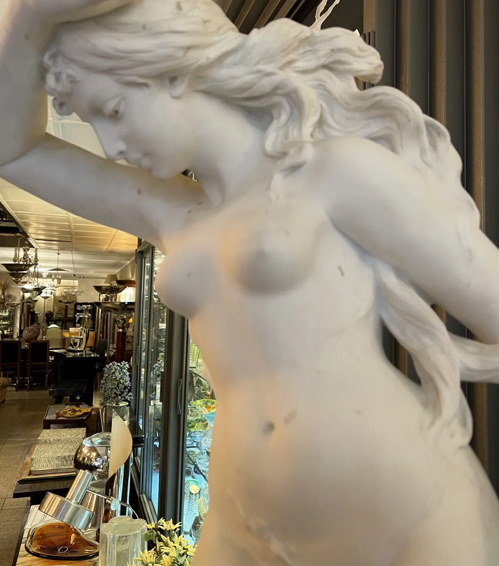 escultura antiga de mulher com cabelo ondulado em ambiente de antiguidades