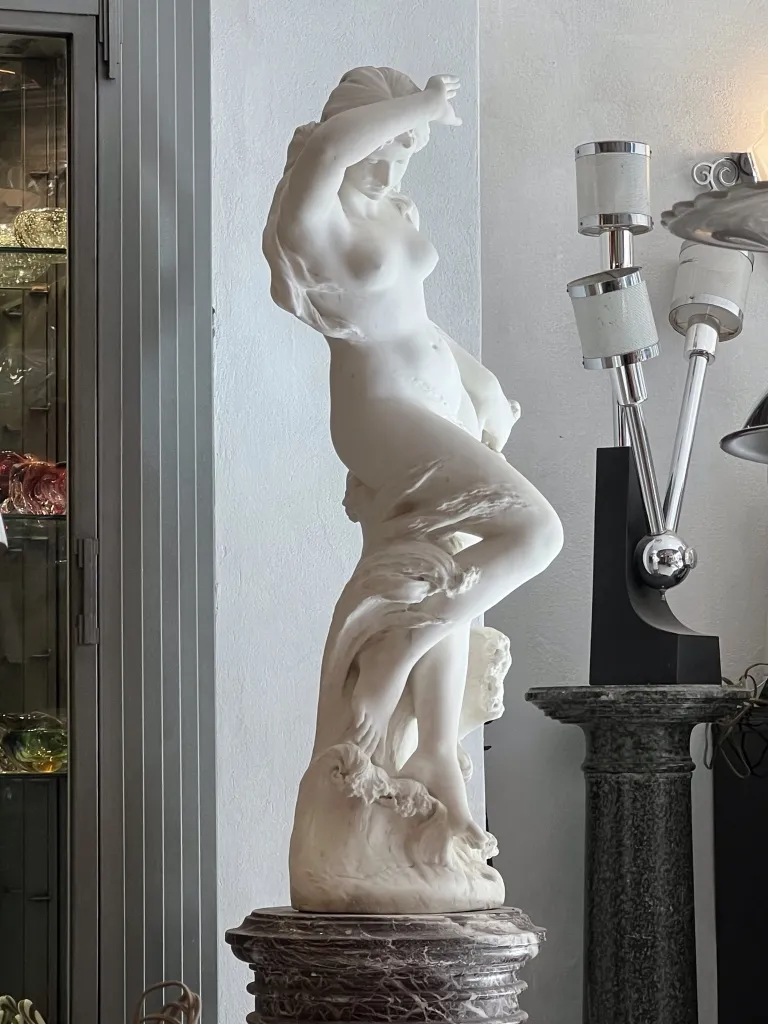 Bonita escultura antiga representando uma figura feminina, elegantemente ambientada.