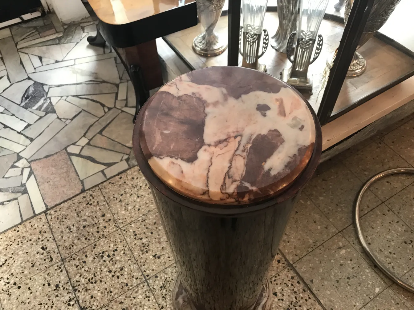 antique column with decorative top and round base, background with other items