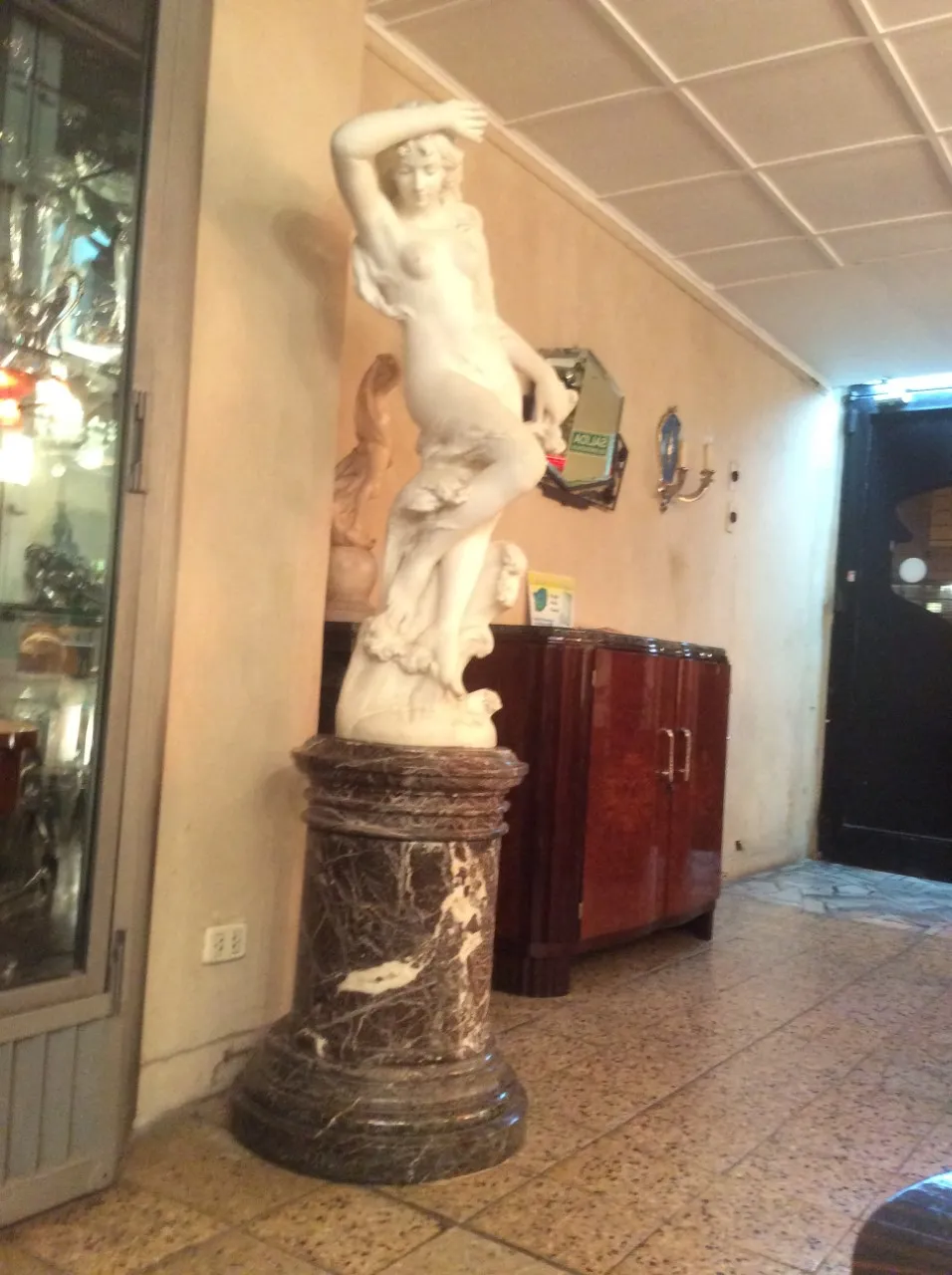 scultura antica con figura femminile e base decorata