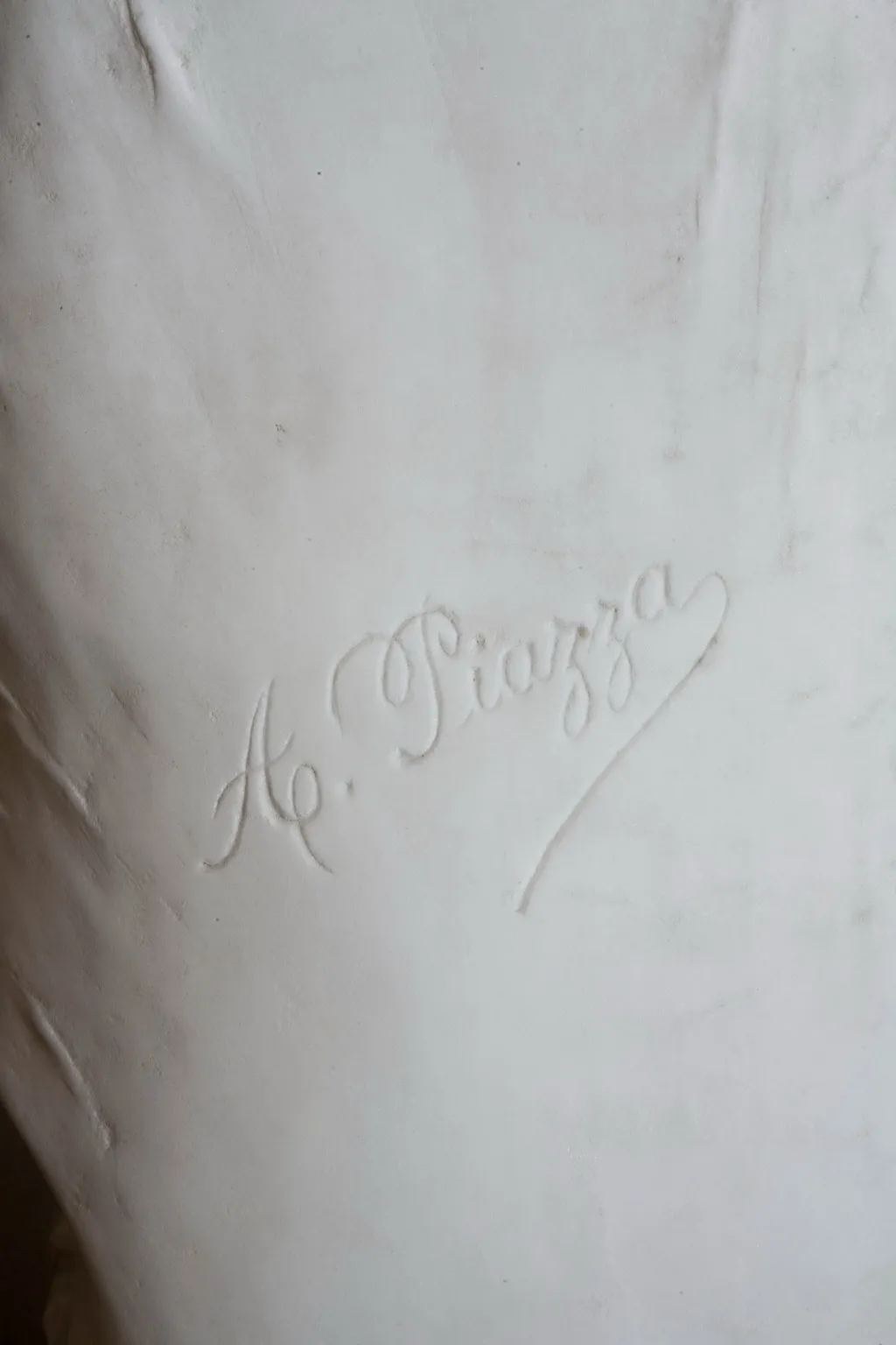 Escultura antigua con firma de A. Piazza, con detalle de color blanco y texturas suaves.