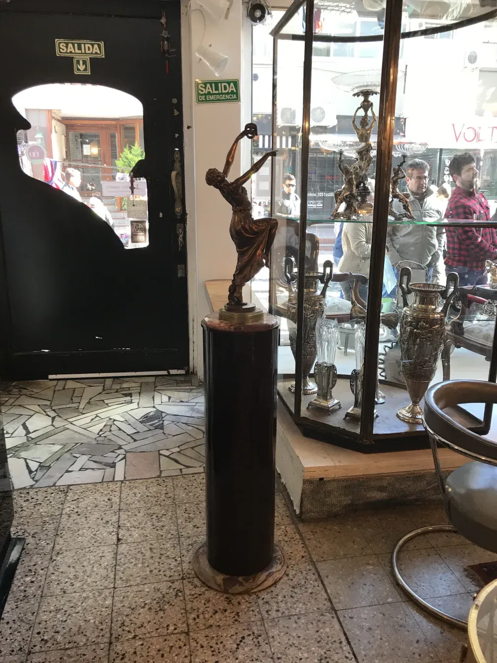 antica colonna con figura decorativa in cima e sfondo del negozio.