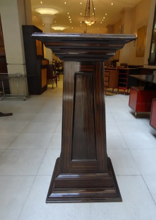 Columna antigua decorativa con detalles estilizados en un entorno elegante.