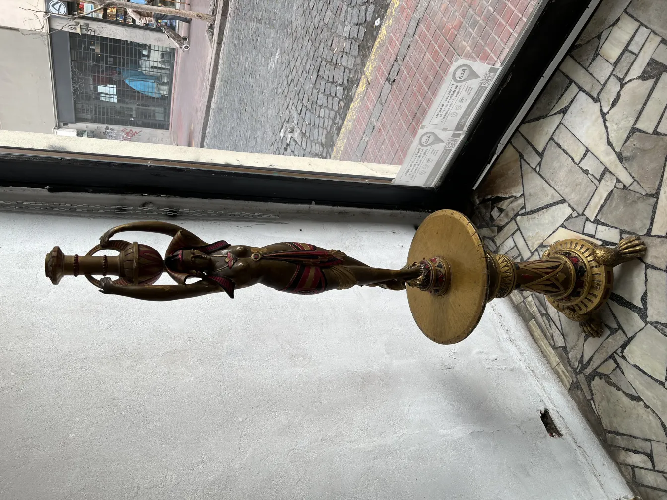 Scultura antica di donna che tiene un bicchiere con dettagli decorativi.