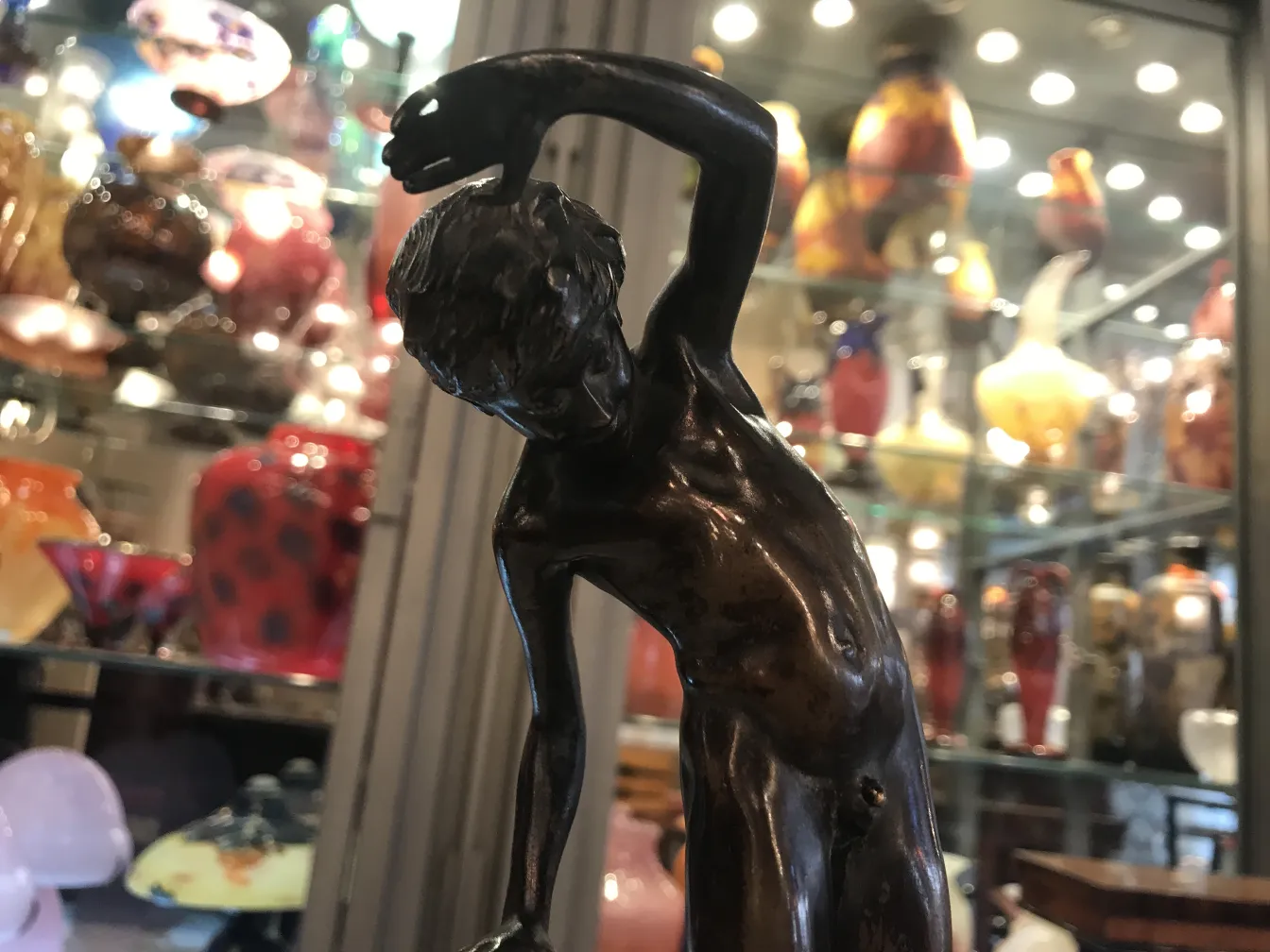 escultura antigua de un hombre con un gesto dinámico, en un entorno de antigüedades coloridas.