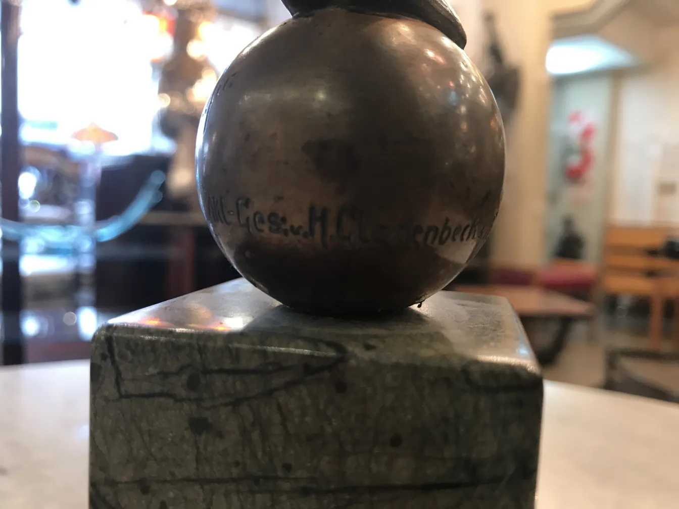 scultura antica con forma sferica e base quadrata in un ambiente museale