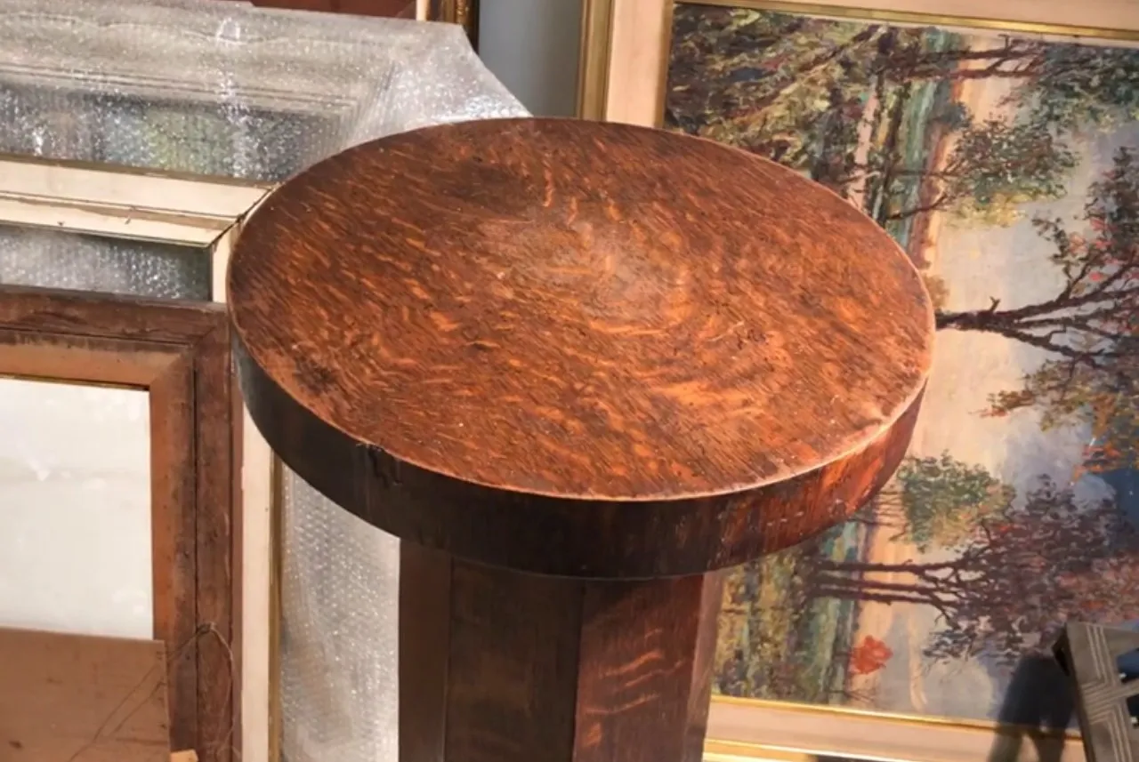 columna antigua con un acabado de madera oscuro, rodeada de cuadros