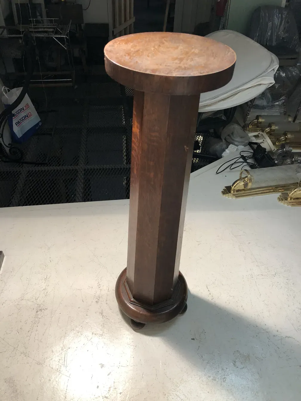 columna antigua con base decorativa circular en un ambiente neutro