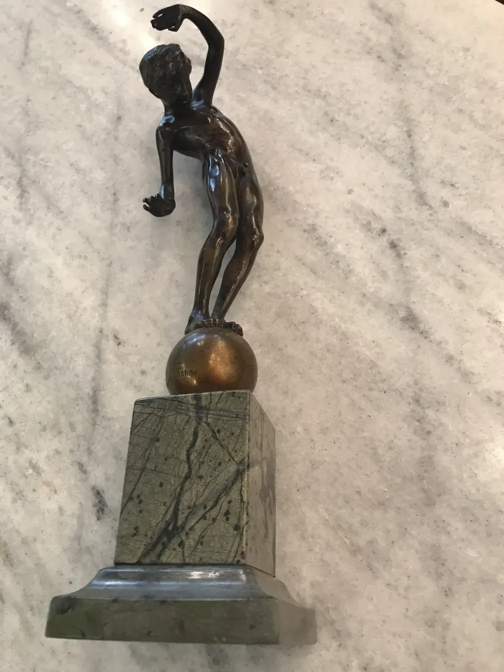 escultura antigua con figura masculina en posesión dinámica sobre pedestal