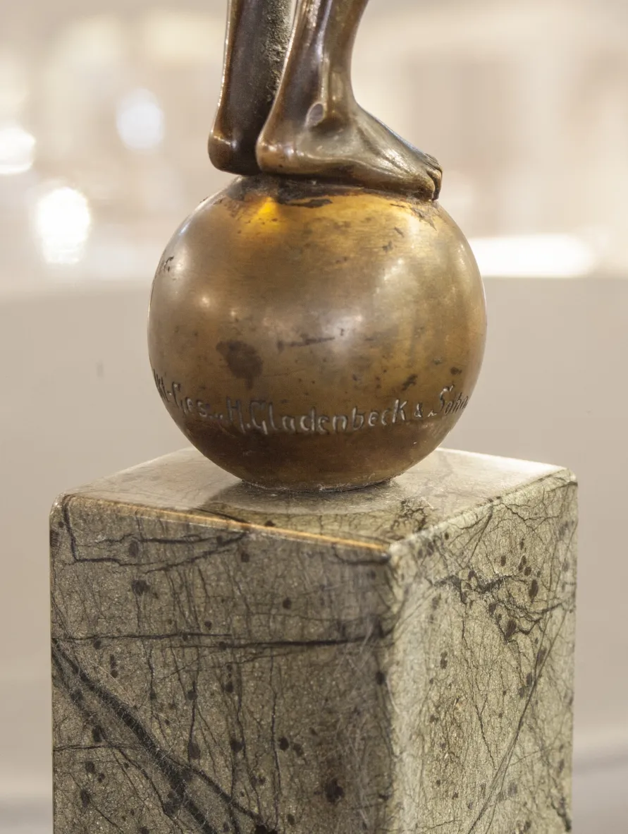 sculpture antique avec figure debout sur une boule sur base décorative