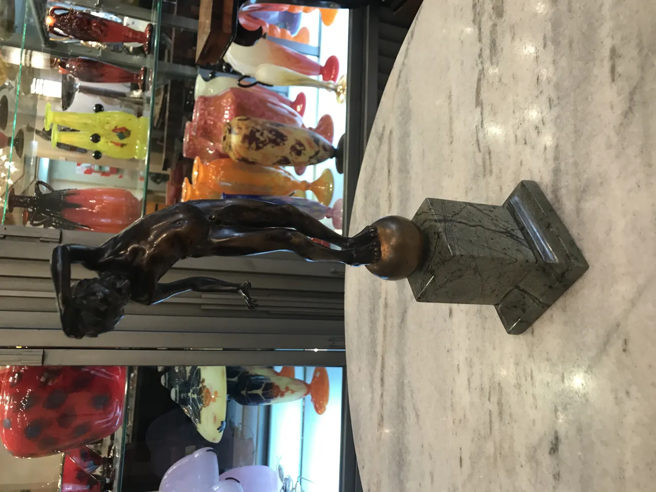 Antike Skulptur eines Mannes in künstlerischer Pose auf Sockel.