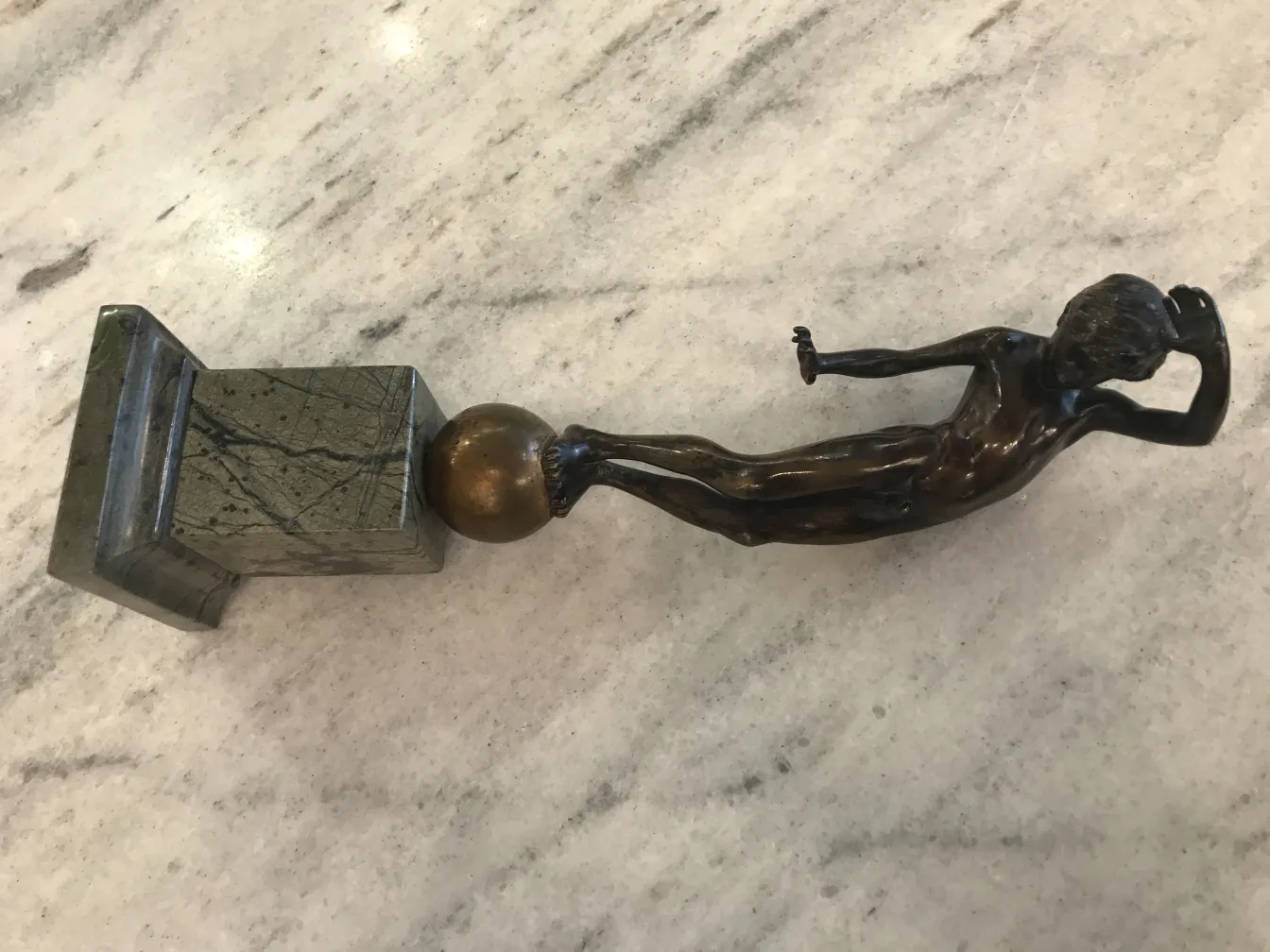 escultura antiga de um homem em posição relaxada em base