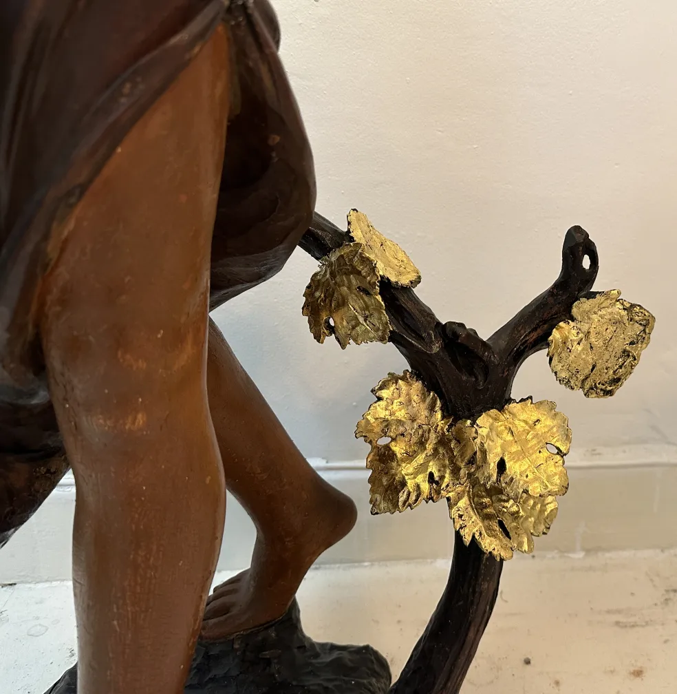 Antike Skulptur einer menschlichen Figur mit hervorgehobenen goldenen Blättern.