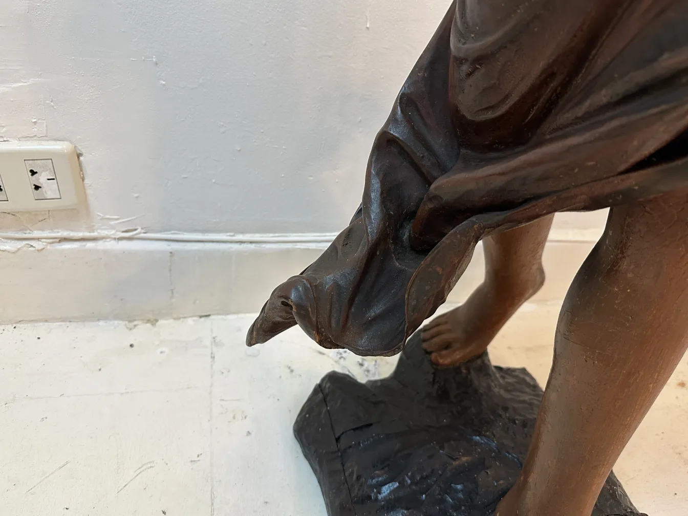 Dettaglio di una scultura antica che mostra un piede e tessuto drappeggiato.