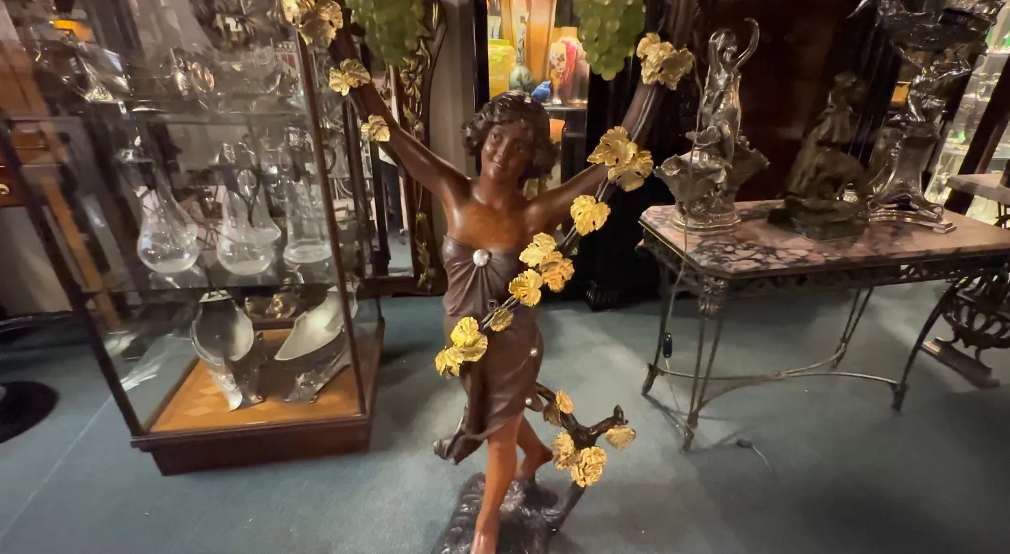 escultura antigua de mujer rodeada de hojas doradas en un ambiente clásico